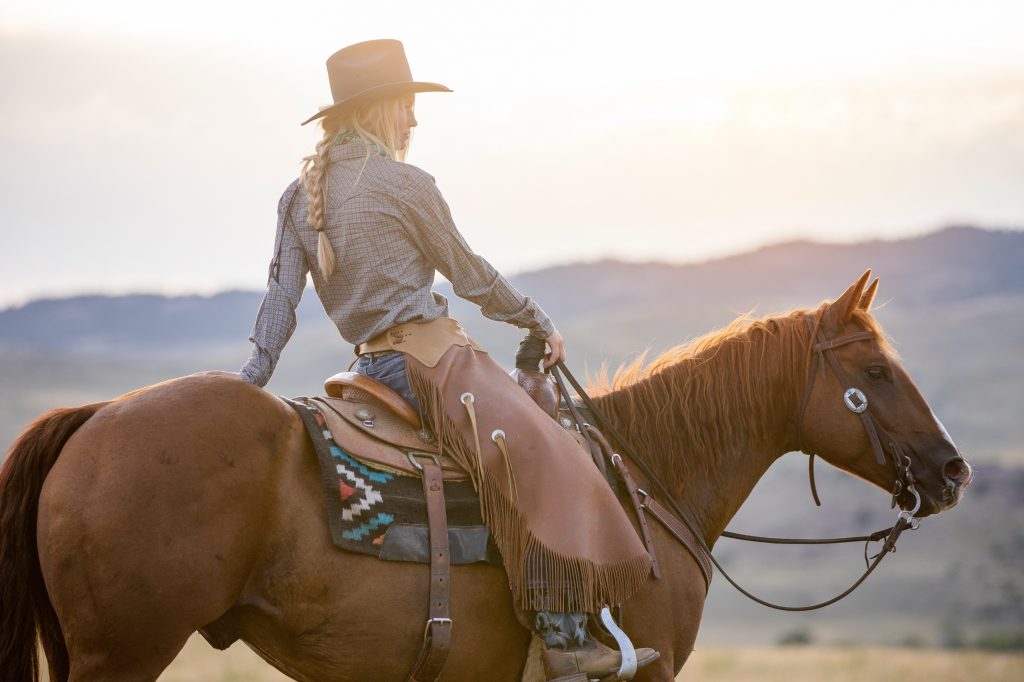 Cowgirl sitting on horse with mountains in the background
